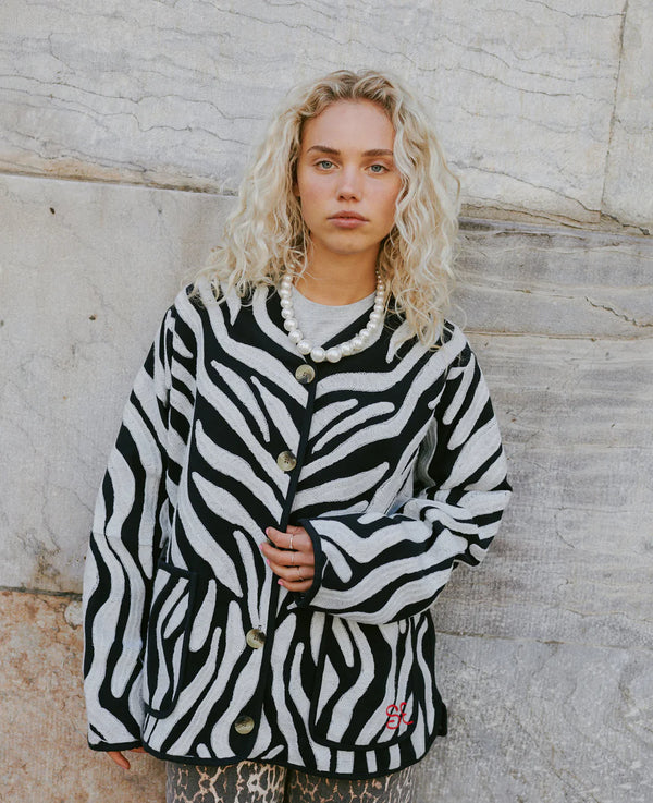 Person wearing a zebra-patterned jacket against a stone wall.
