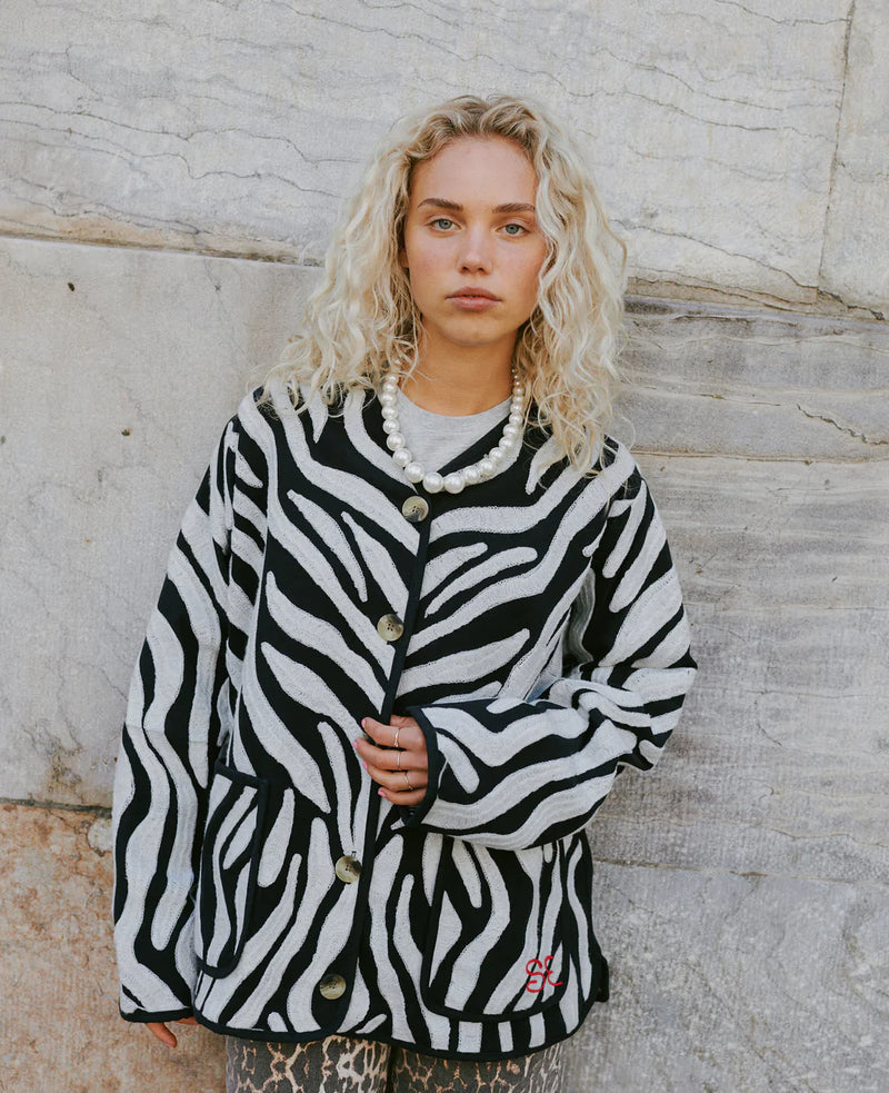 Person wearing a zebra-patterned jacket against a stone wall.