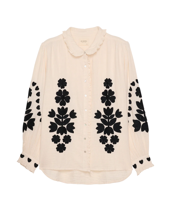 Beige blouse with black floral patterns on sleeves and collar against a white background