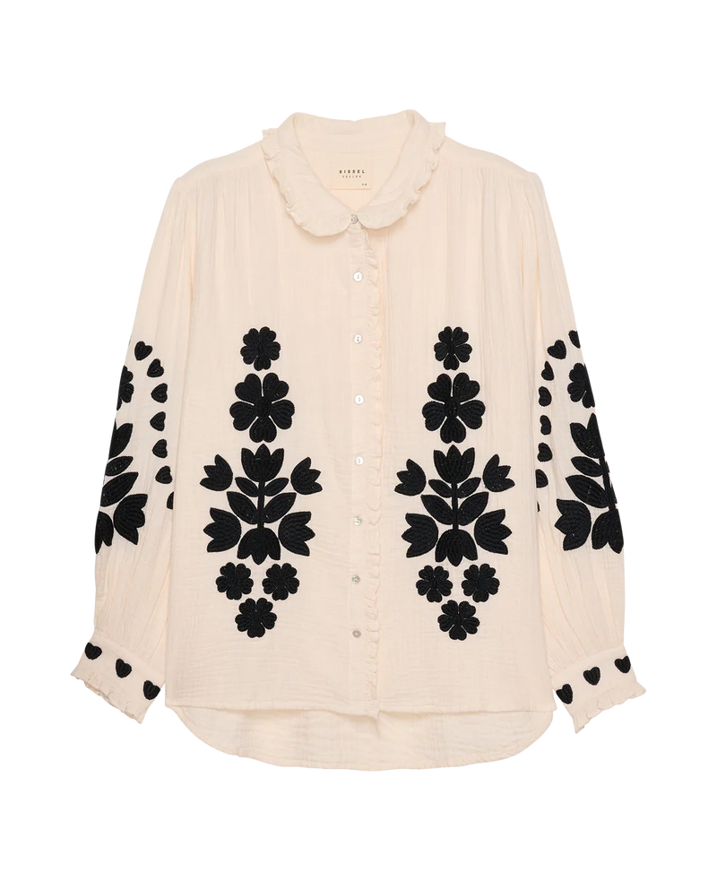 Beige blouse with black floral patterns on sleeves and collar against a white background